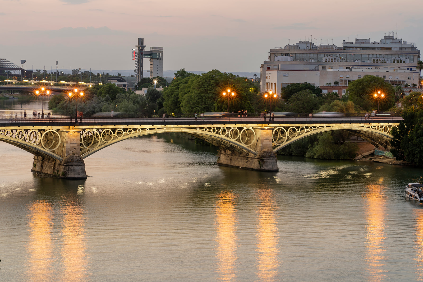 El Puente de Triana iluminado sobre el Guadalquivir al anochecer